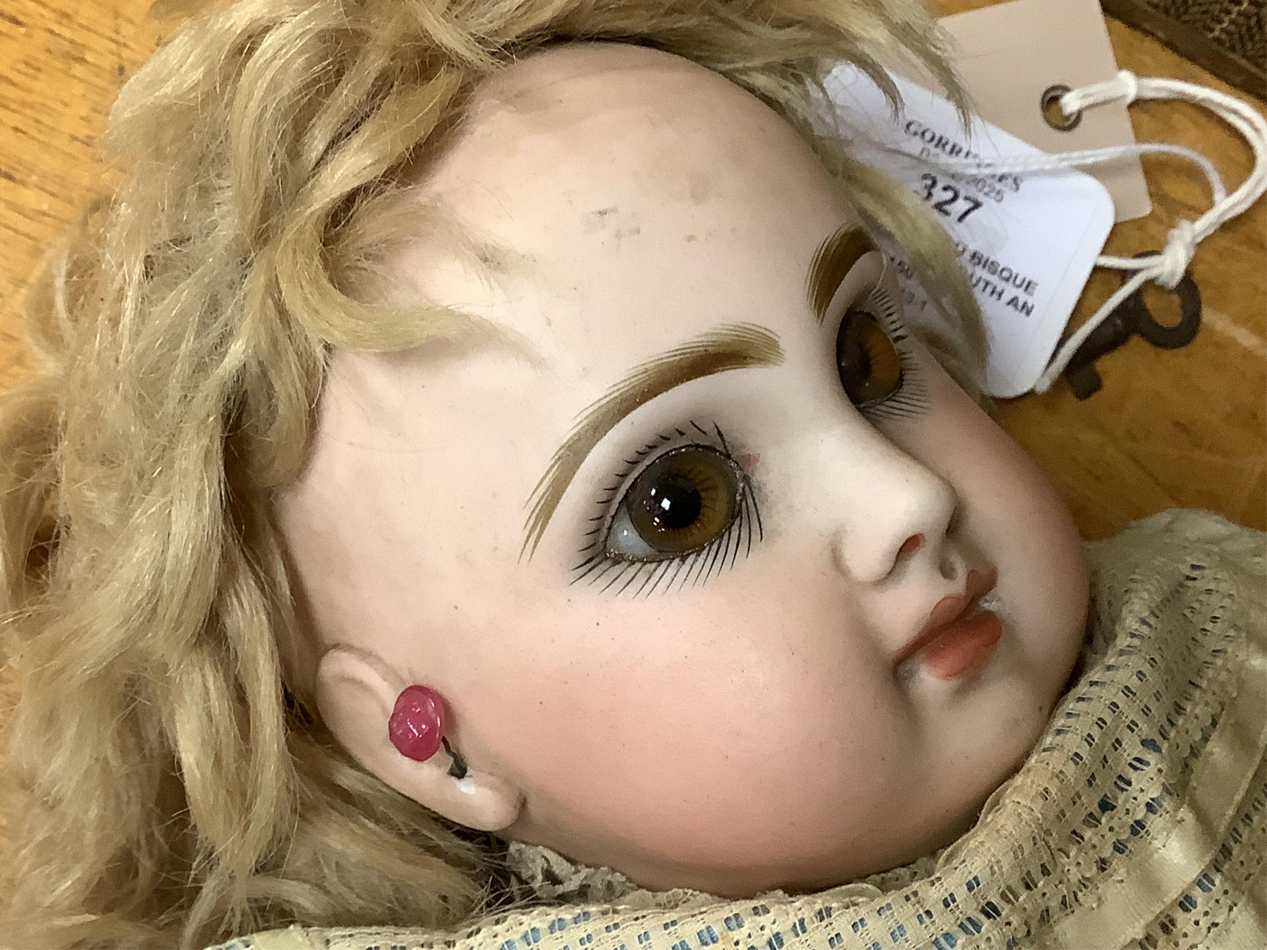 A Tête Jumeau bisque doll, closed mouth and paperweight eyes, jointed wood and composition body, two other French bisque dolls and assorted clothing, all contained within a three-layer wood and metal-bound cabin trunk, J